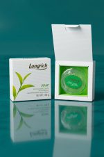 Longrich soap packaging on a reflective surface with a teal background