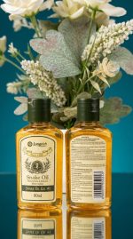 Two bottles of Longrich Snake Oil with a floral arrangement on a reflective surface.