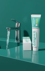 Longrich toothpaste tube and packaging on a teal surface with a faucet.