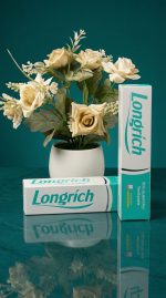 Longrich toothpaste packaging with a vase of flowers on a reflective surface