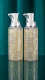 Two bottles of Longrich body care product on a reflective surface with a green curtain background.
