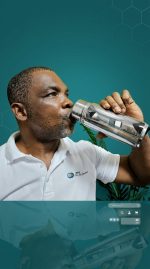 Man drinking from a silver water bottle against a teal background