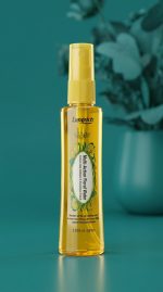 Yellow spray bottle with floral design on a teal background